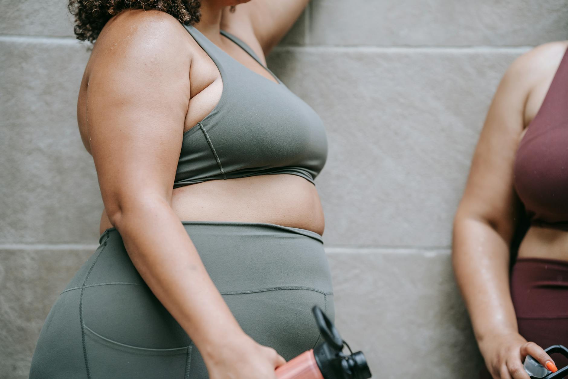 Dwie wysportowane kobiety w strojach sportowych odpoczywają z bidonami