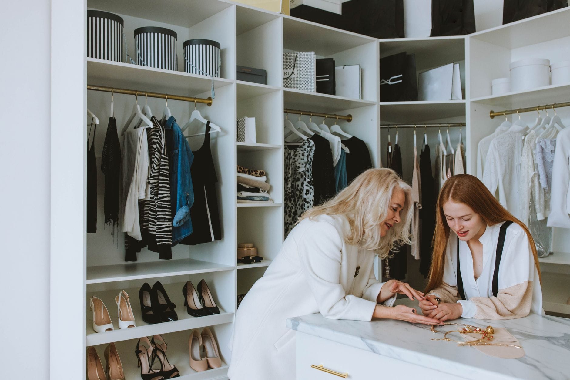 Starsza i młoda kobieta omawiają ubrania w eleganckiej butikowej garderobie